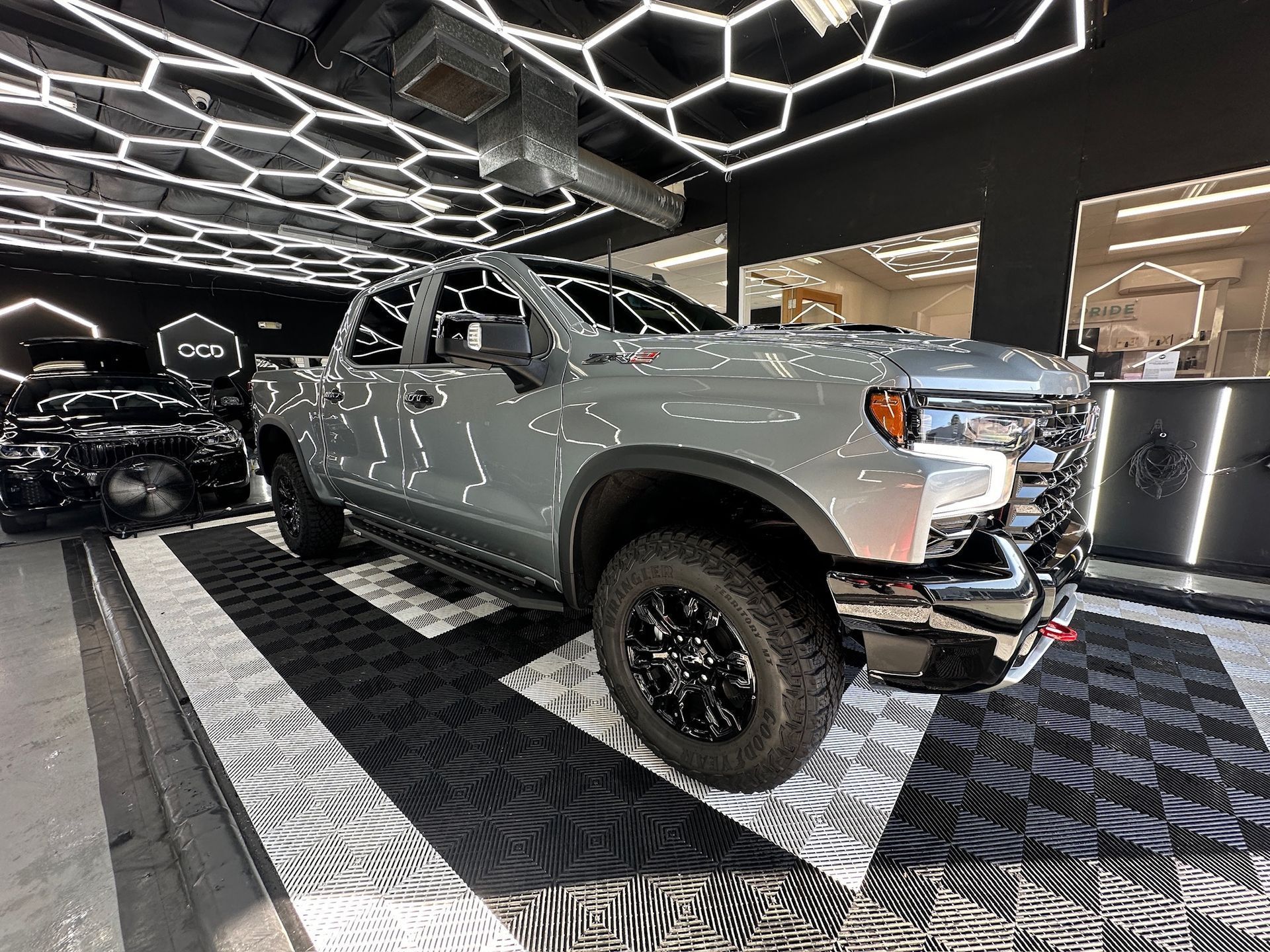 Silver off-road pickup truck displayed indoors under geometric ceiling lights