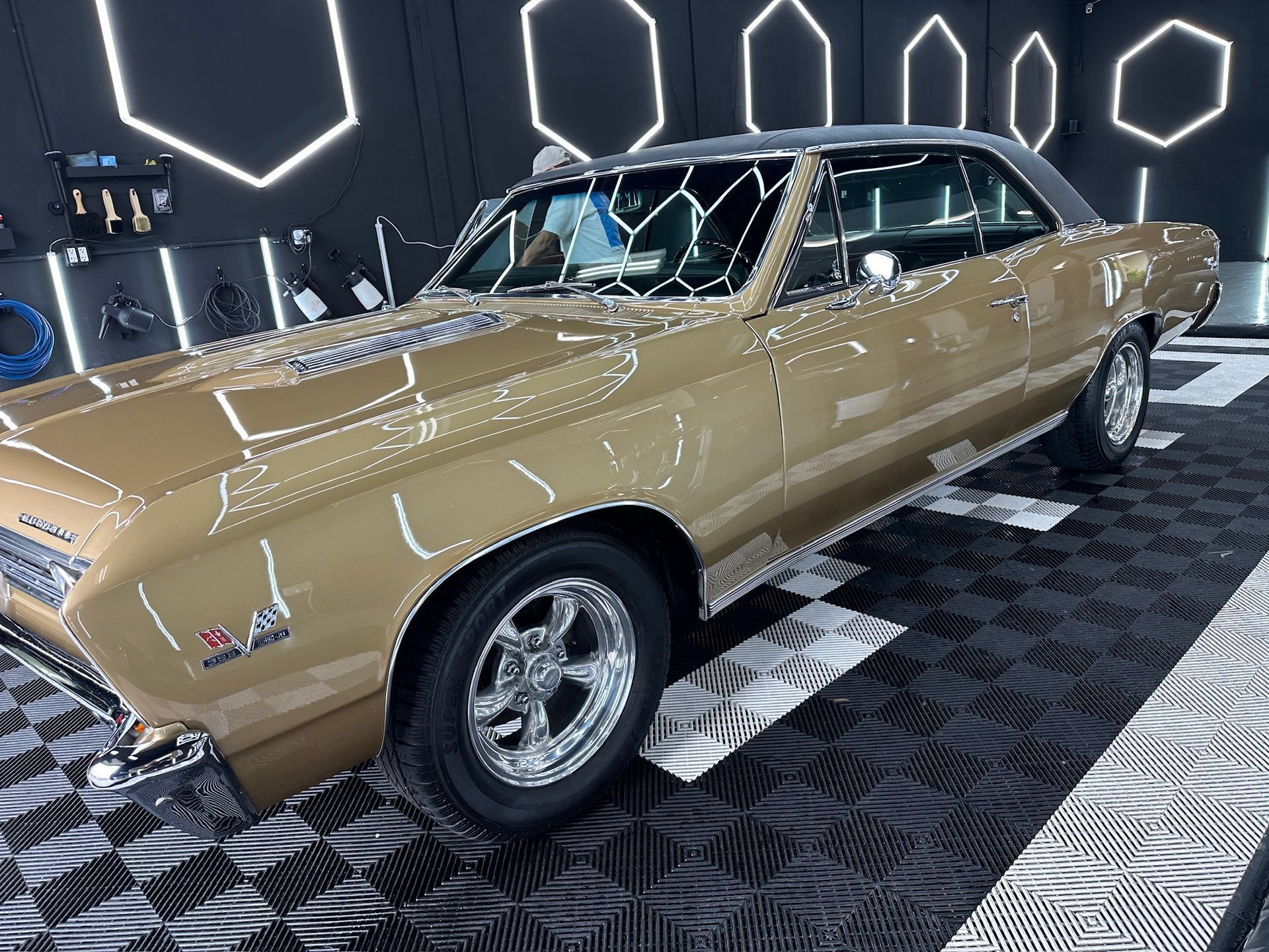 Gold classic car in a showroom with neon wall lights and black patterned floor