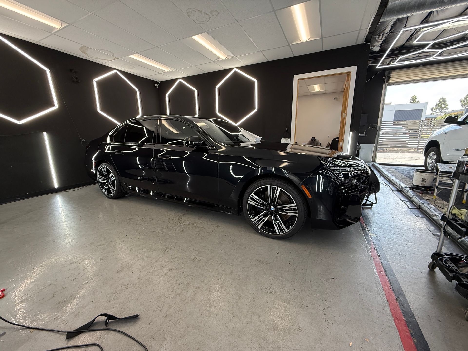White SUV in a modern showroom with geometric LED ceiling lights and black walls
