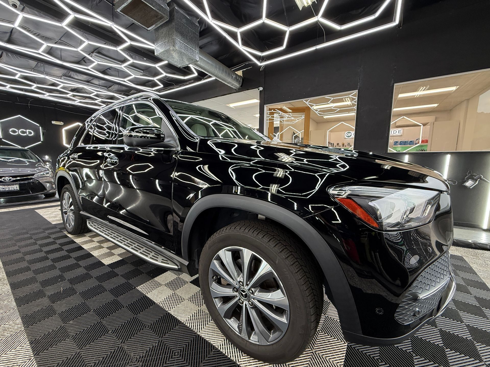 Black SUV displayed in a showroom with patterned floor and geometric ceiling lights