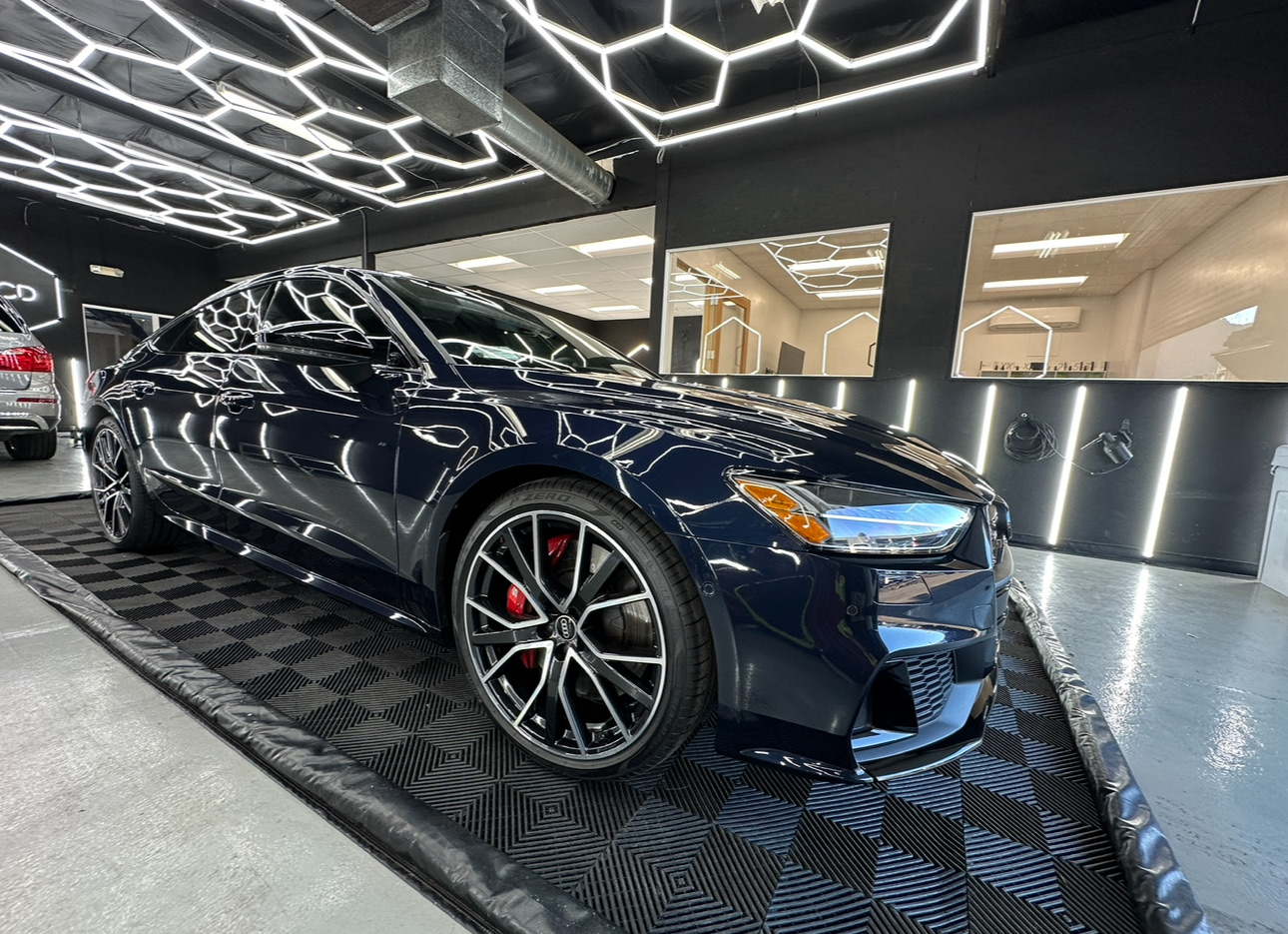 Dark blue luxury sports car in a showroom with geometric ceiling lights
