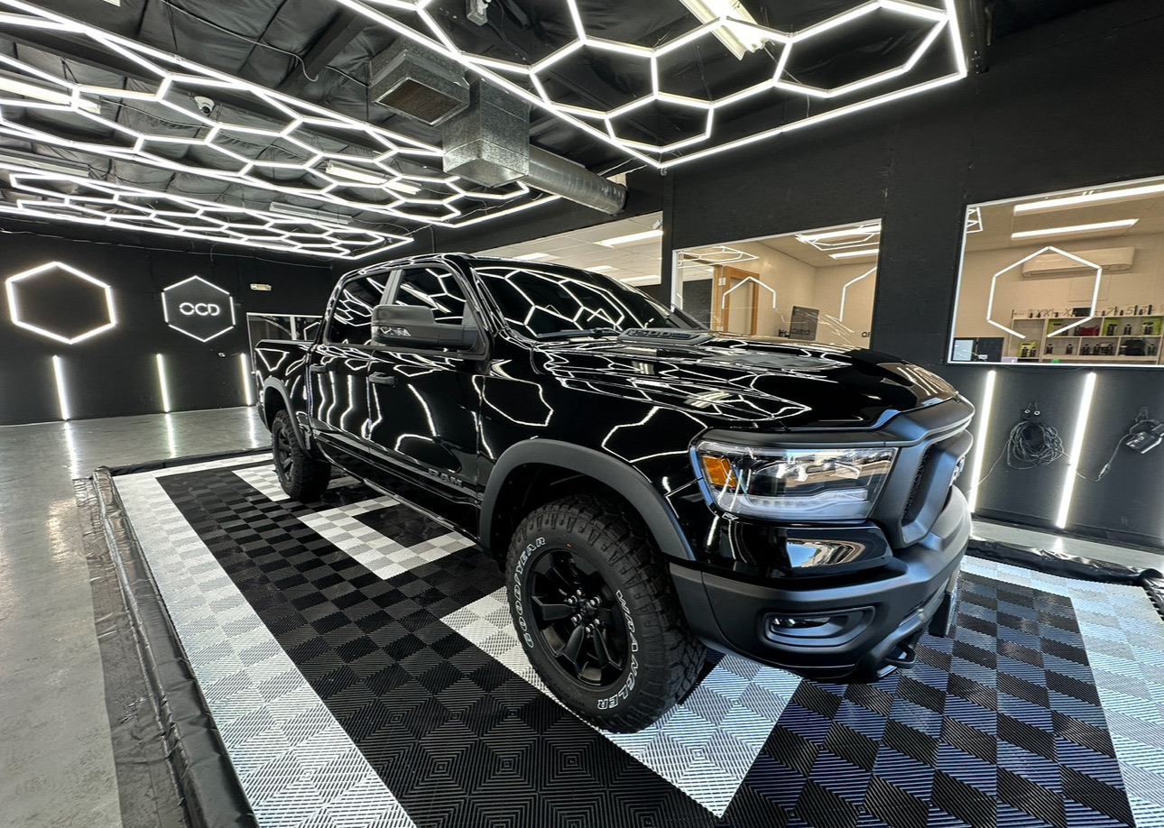 Black pickup truck displayed in a showroom with geometric ceiling lights and patterned floor