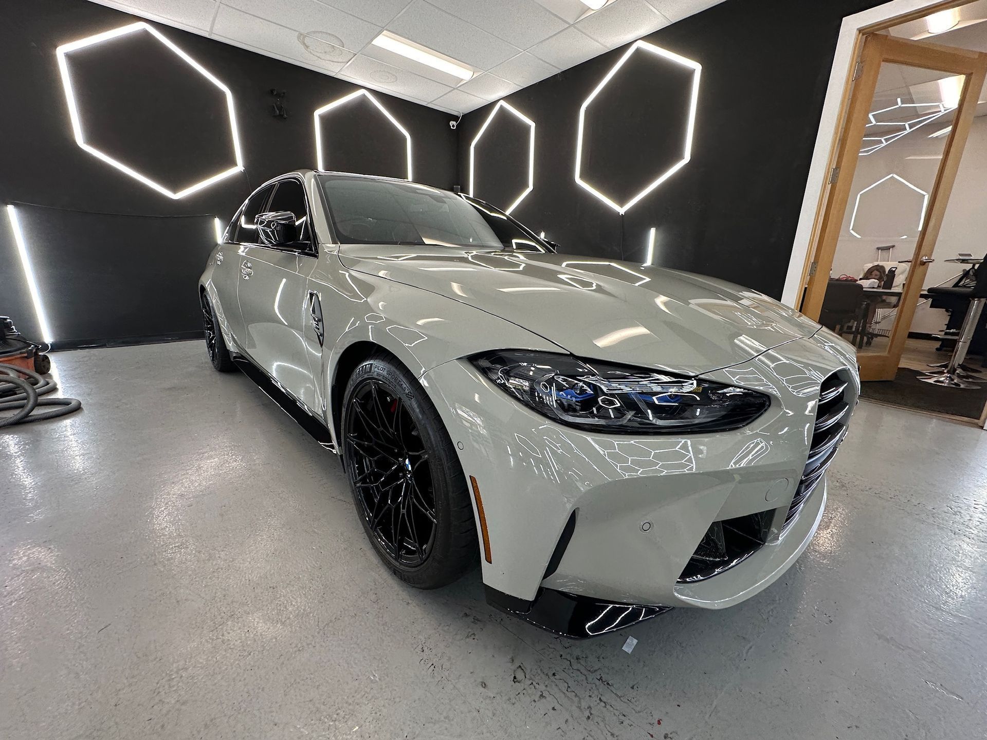 White sports sedan in a showroom with hexagonal wall lights and a glossy floor