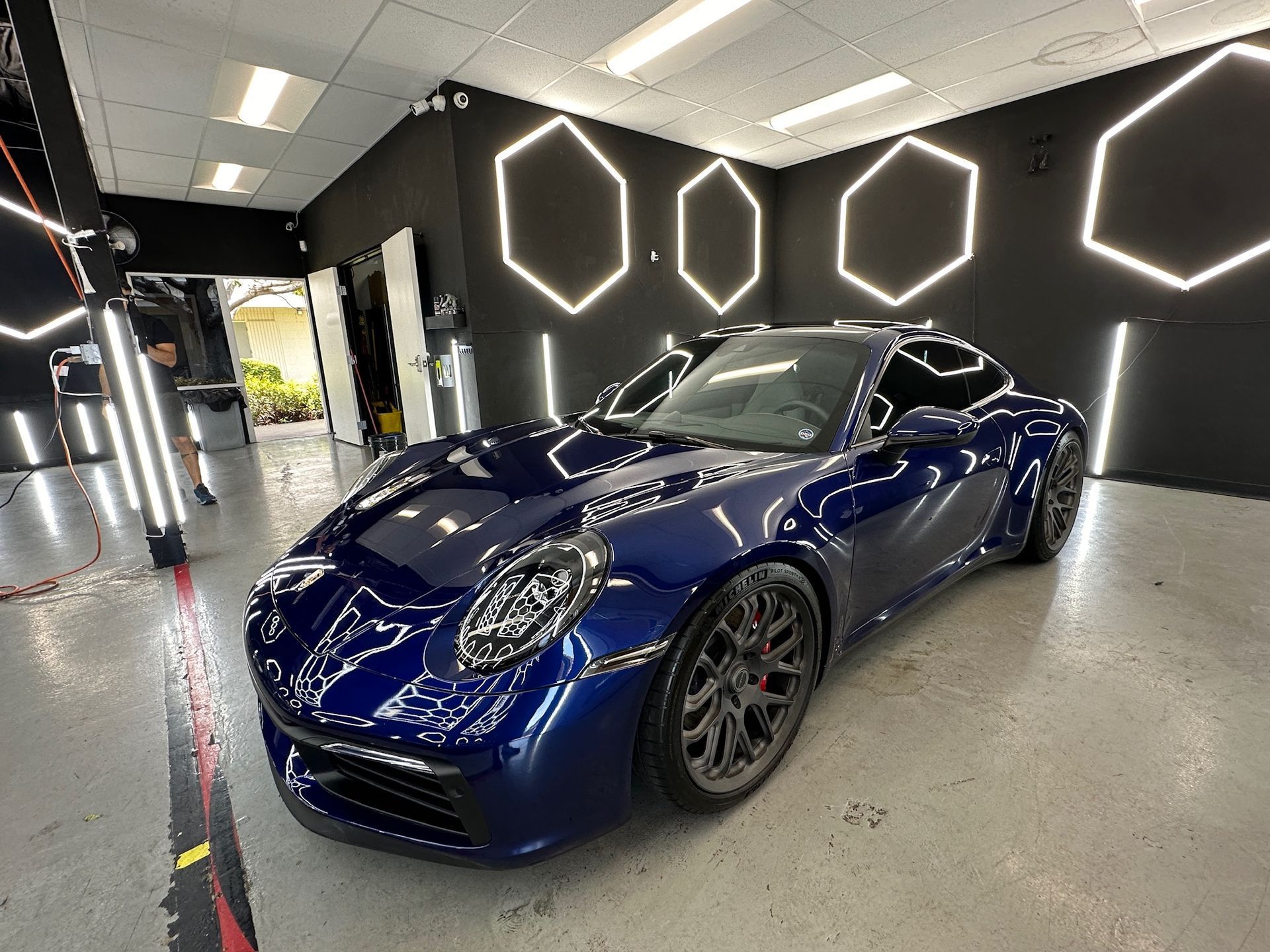 Blue sports car in a showroom with black walls and hexagonal lights
