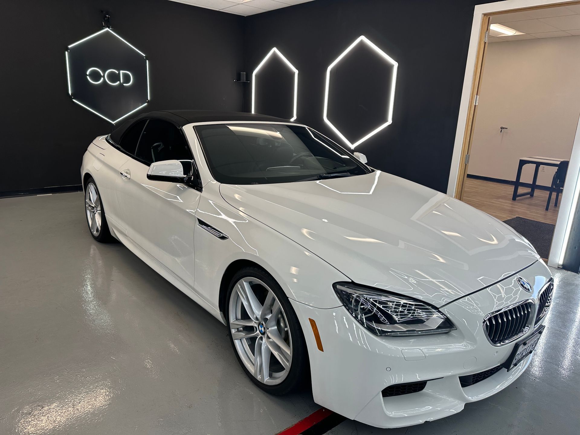 White BMW coupe in a showroom with black walls and neon hexagon lights