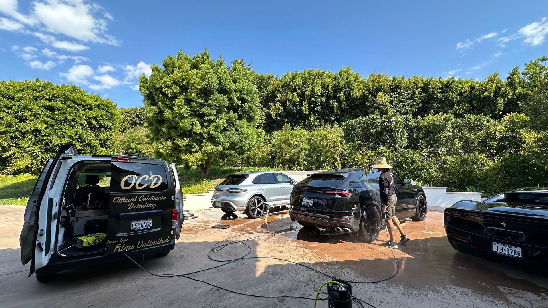 Several vehicles parked on a dirt lot beside dense green trees under a blue sky                                                                                                                                                                                                                                                                                                                                                                                                                                                                                                                                                                                                                                                                                                                                                                                                                                                                                                                                                                                                                                                                                                                                                                                                                                                                                                                                                                                                                                                                                                                                                                                                                                                                                                                                                                                                                                                                                                                                                                                                                                                                                                                                                                                                                                                                                                                                                                                                                                                                                                                                                                                                                                                                                                                                                                                                                                                                                                                                                                                                                                                                                                                                                                                                                                                                                                                                                                                                                                                                                                                                                                                                                                                                                    