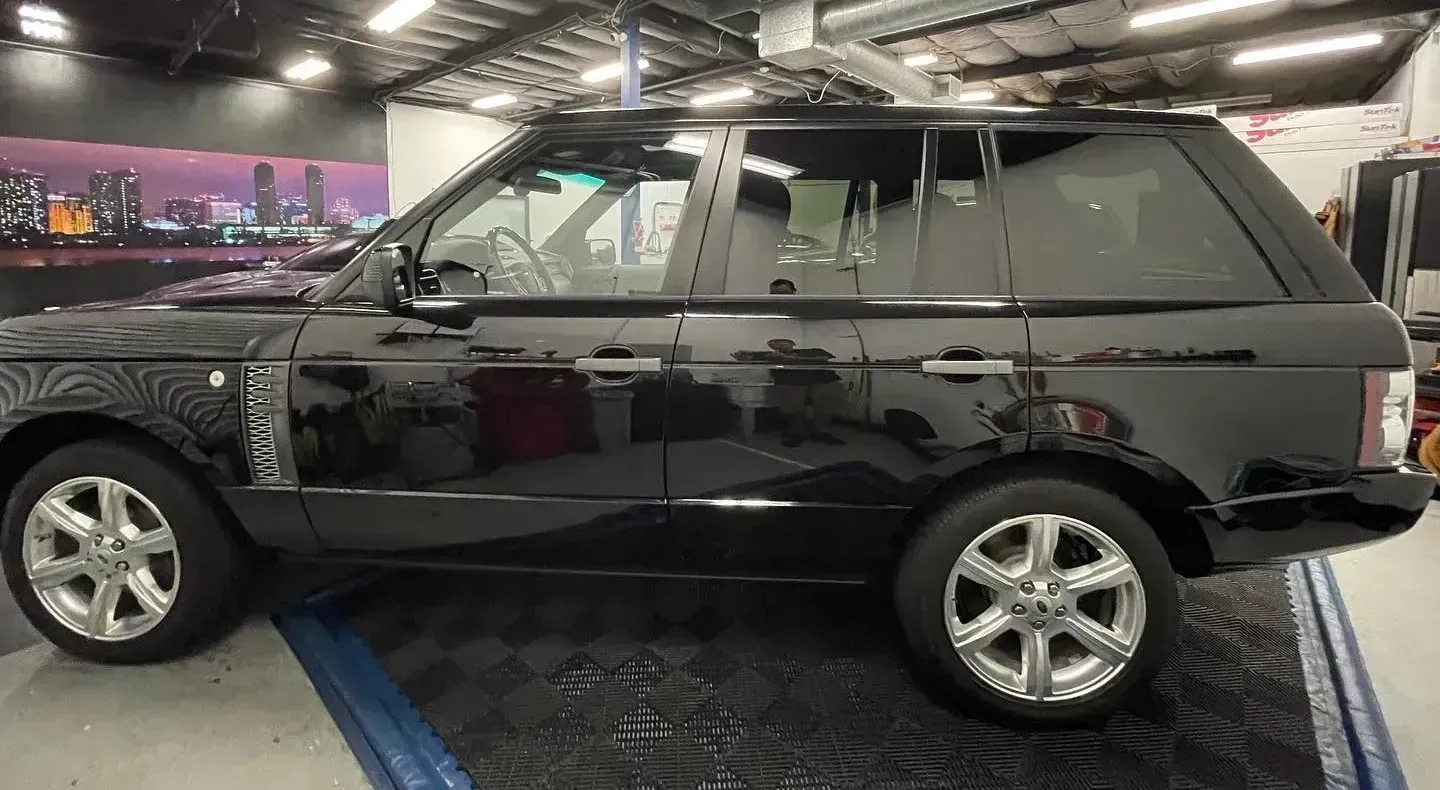 Red sports coupe in a garage on a lift, side view, glossy paint and black wheels