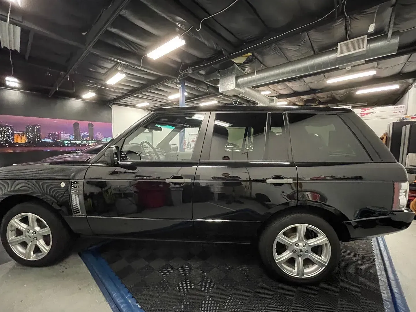 Black Range Rover SUV parked indoors under bright shop lights.