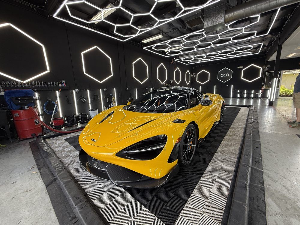 Yellow sports car in a modern showroom with geometric LED ceiling lights
