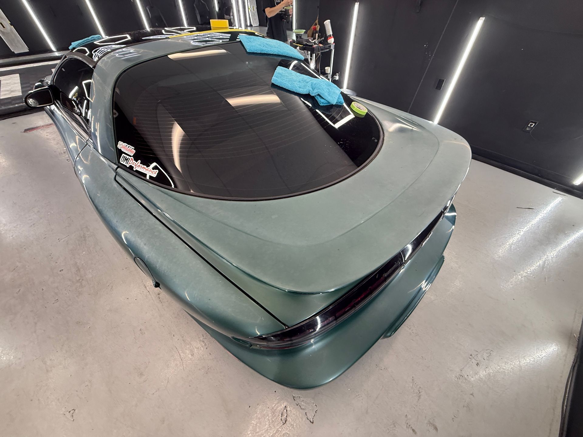 Light green sports car viewed from above in a showroom with dark walls and bright lights