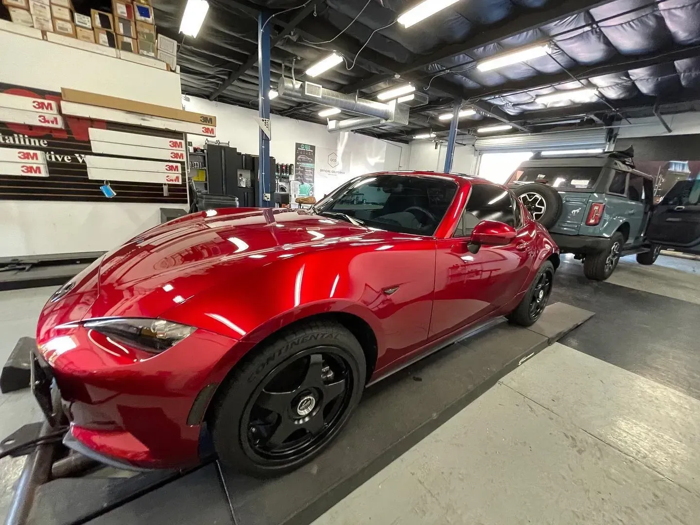 Red sports car in a showroom, viewed from the front-left side.