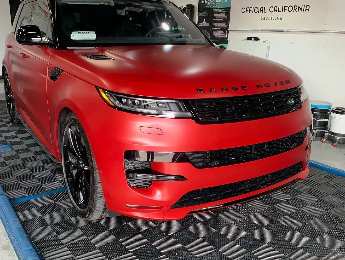 Red Range Rover SUV displayed indoors on a patterned floor, front-left view.