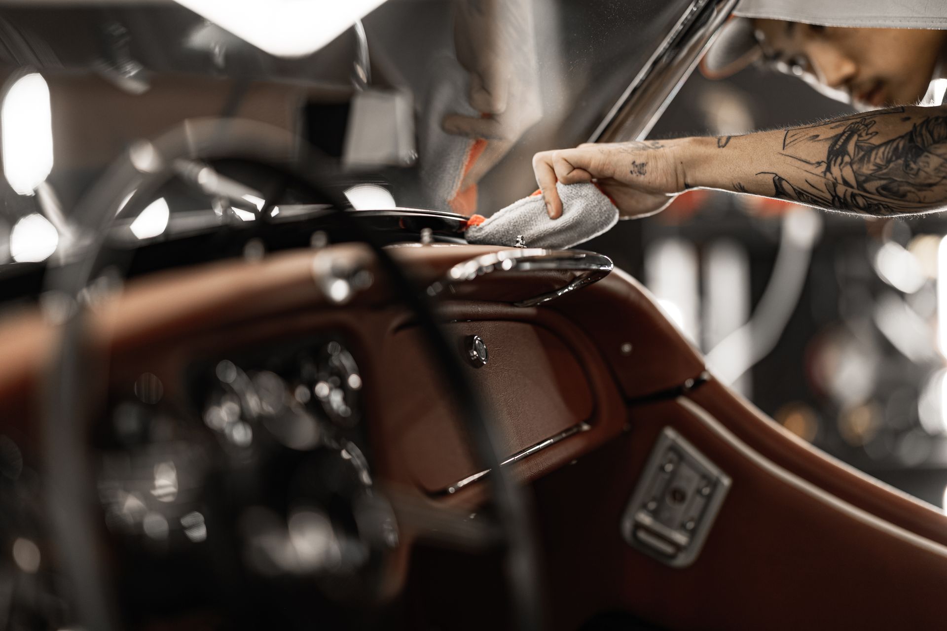 Person polishing a brown car interior with a cloth, close-up view of the dashboard and seat area