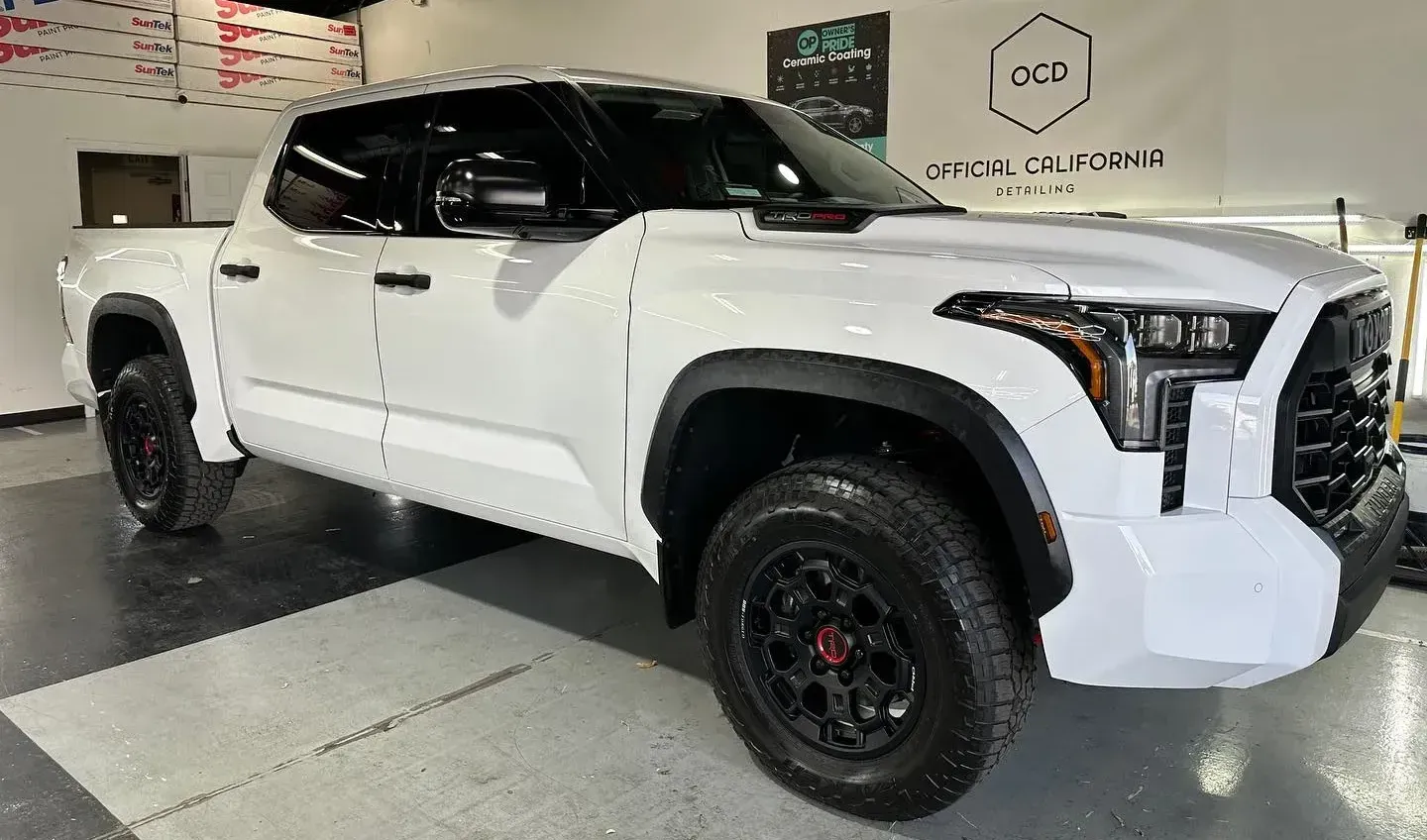 White lifted pickup truck displayed indoors in a showroom, side view.