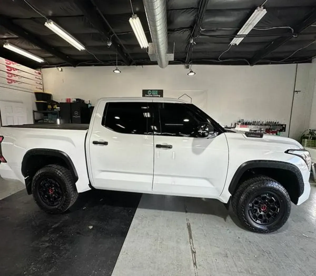 White lifted pickup truck inside an auto shop garage