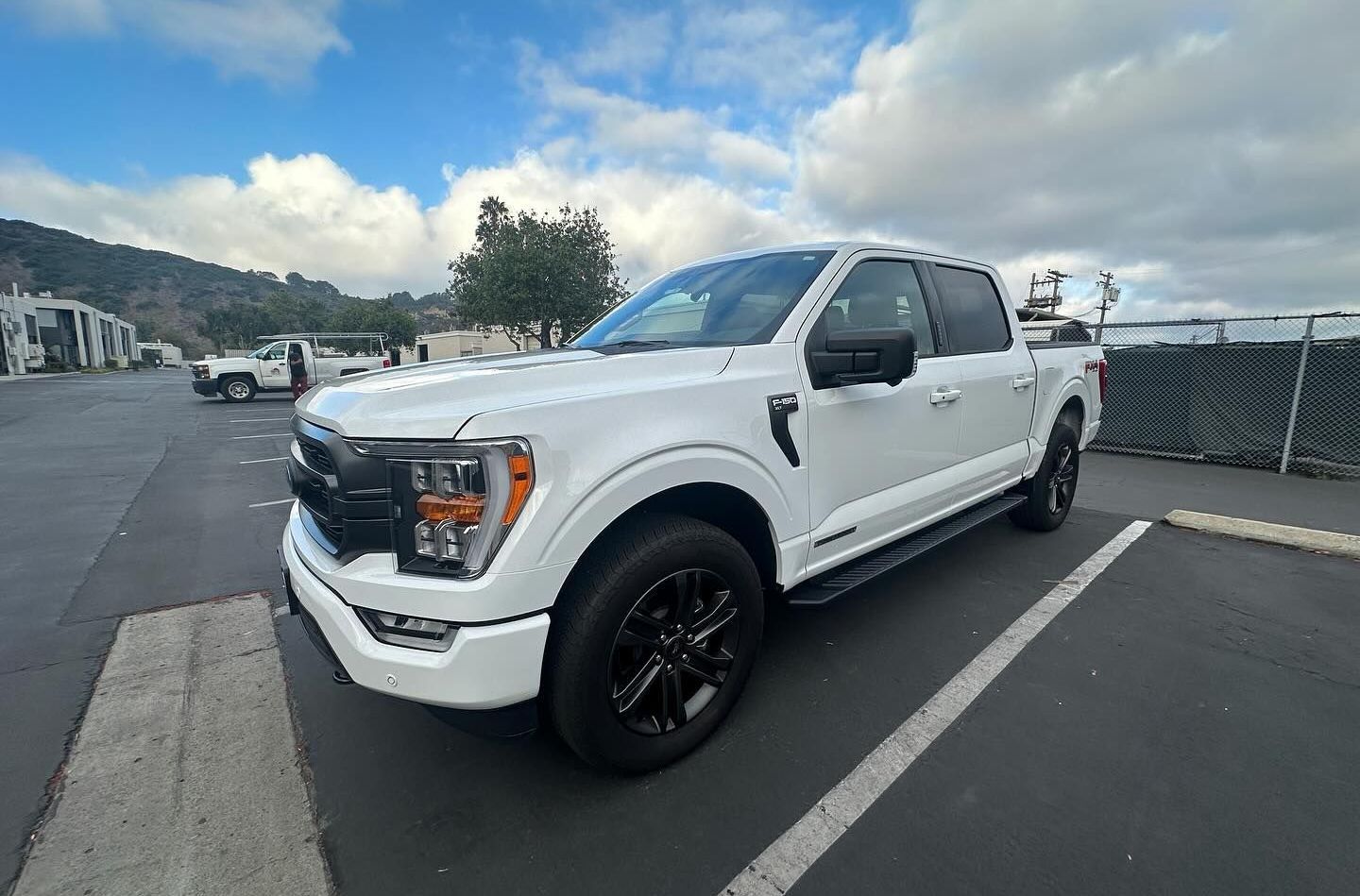 White Ford pickup truck parked in a lot under a cloudy sky