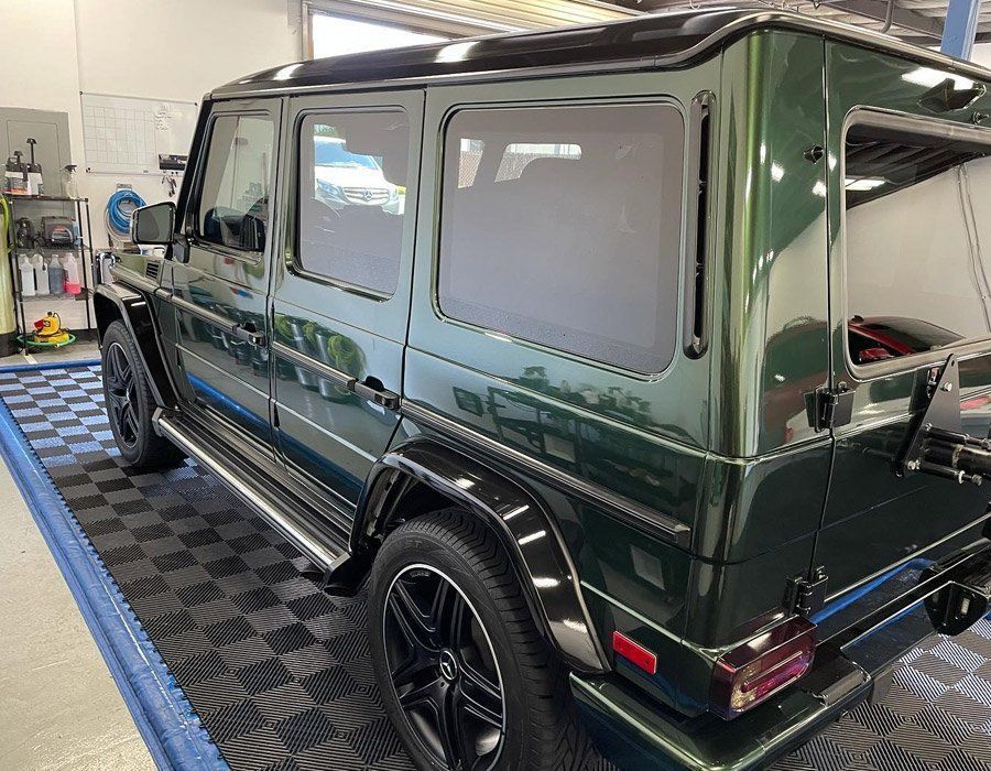 Dark green Mercedes-Benz G-Class SUV in a garage, shown from the rear side.