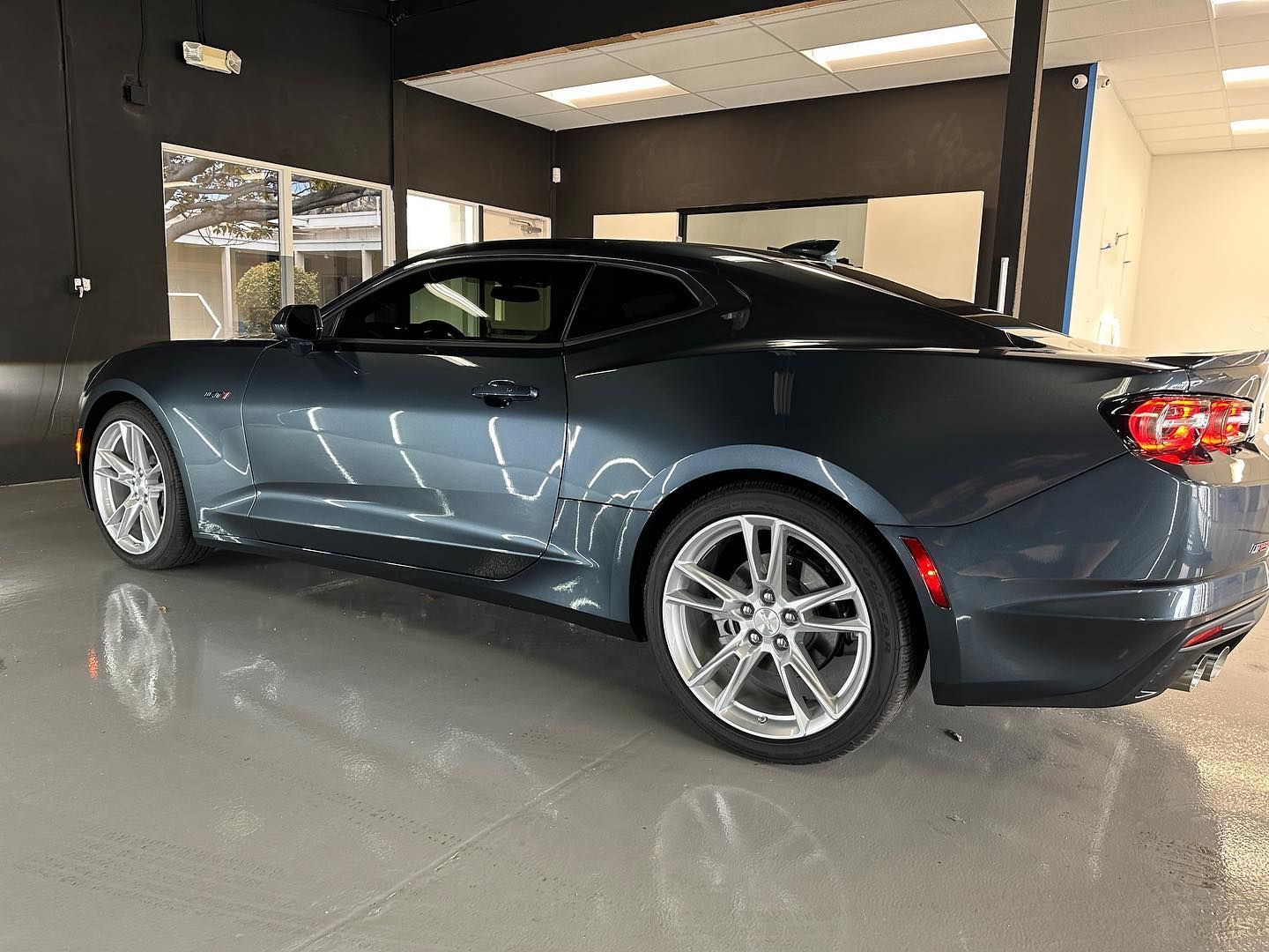 Dark gray coupe parked indoors in a showroom, side view