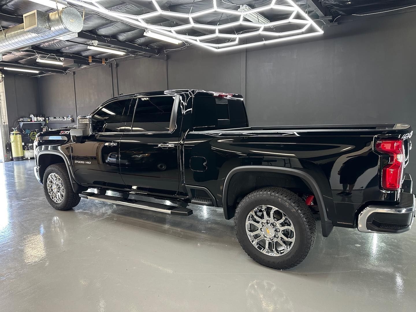Black pickup truck parked indoors under bright geometric ceiling lights.
