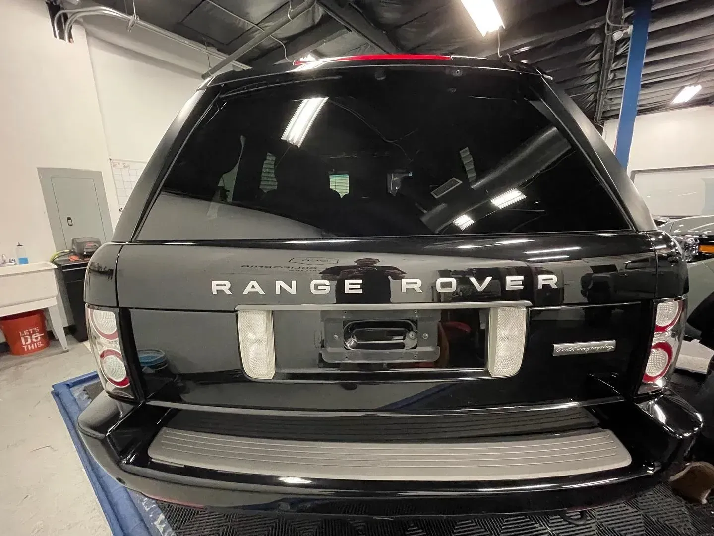 Rear view of a black Range Rover parked indoors in a garage or workshop.