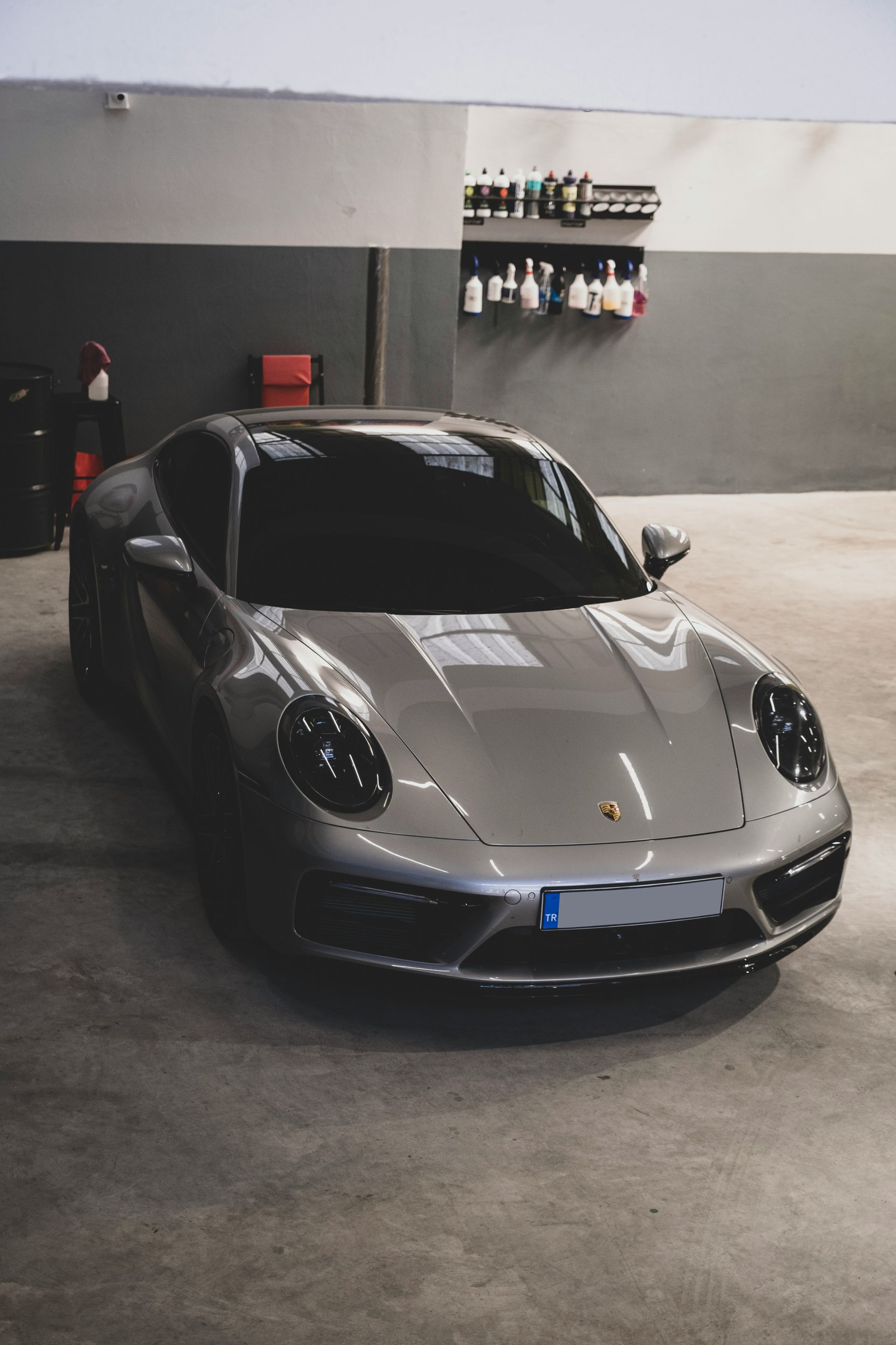 Gray sports car parked in an indoor garage, front view