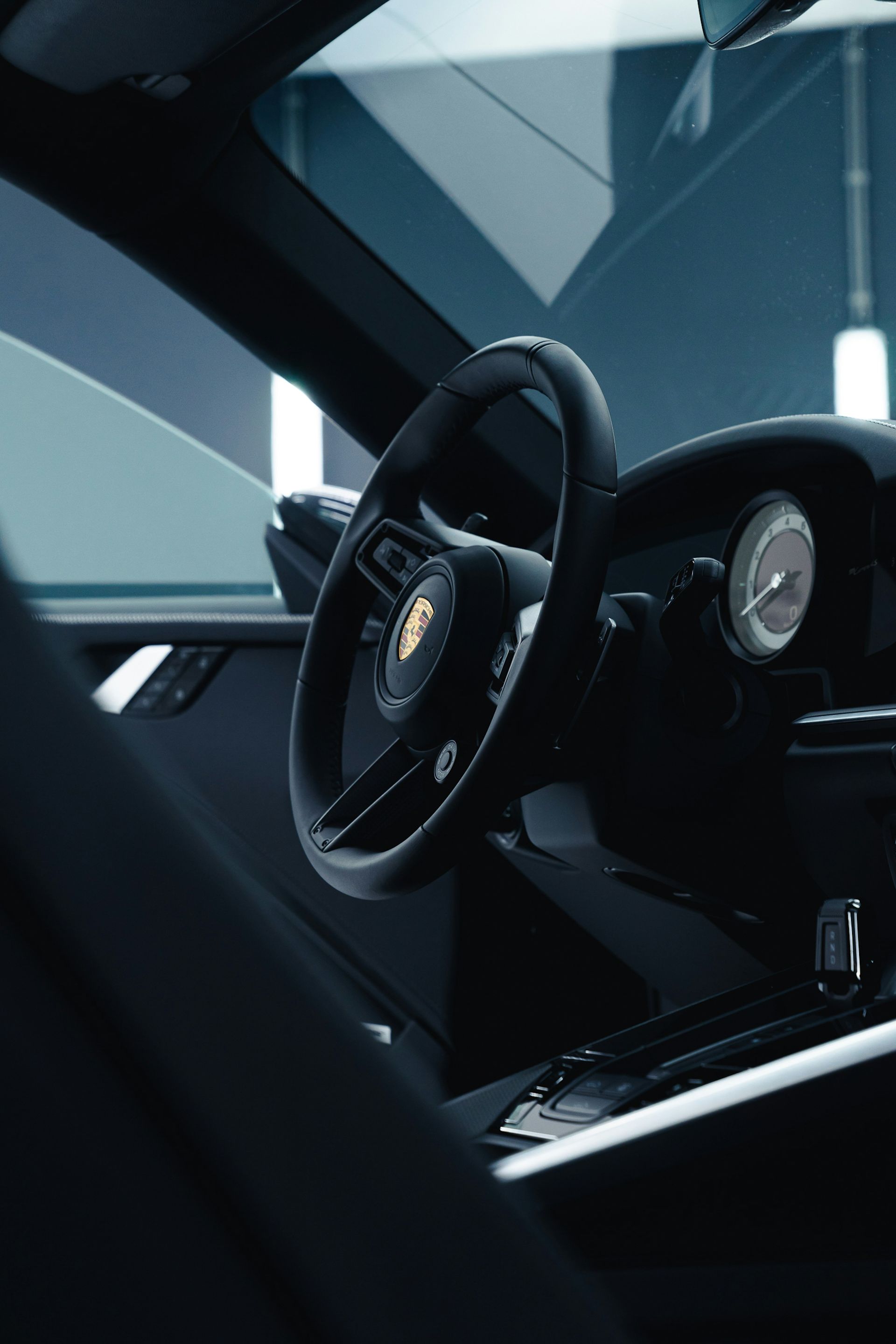 Black sports car interior with steering wheel and dashboard, viewed from the driver’s side