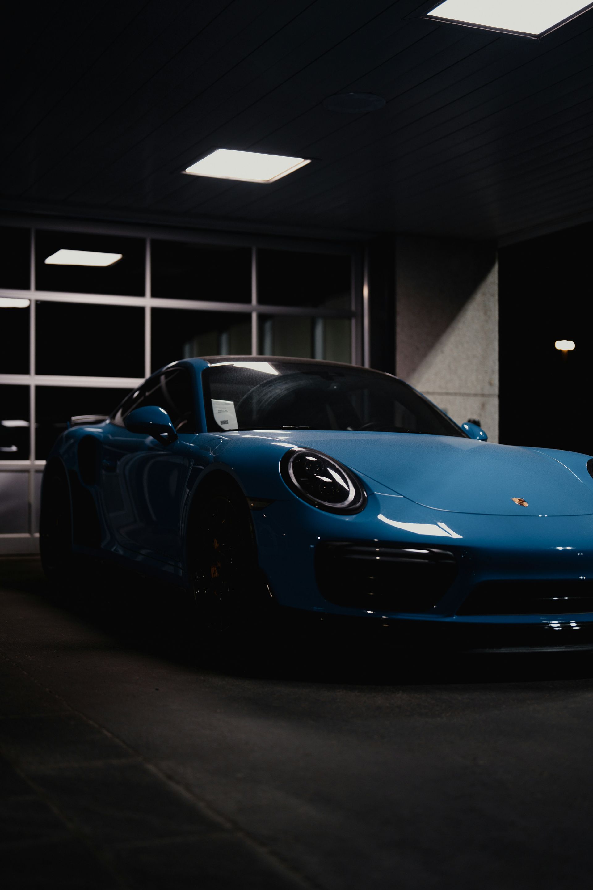 Blue sports car in a dark garage, front view with headlights off