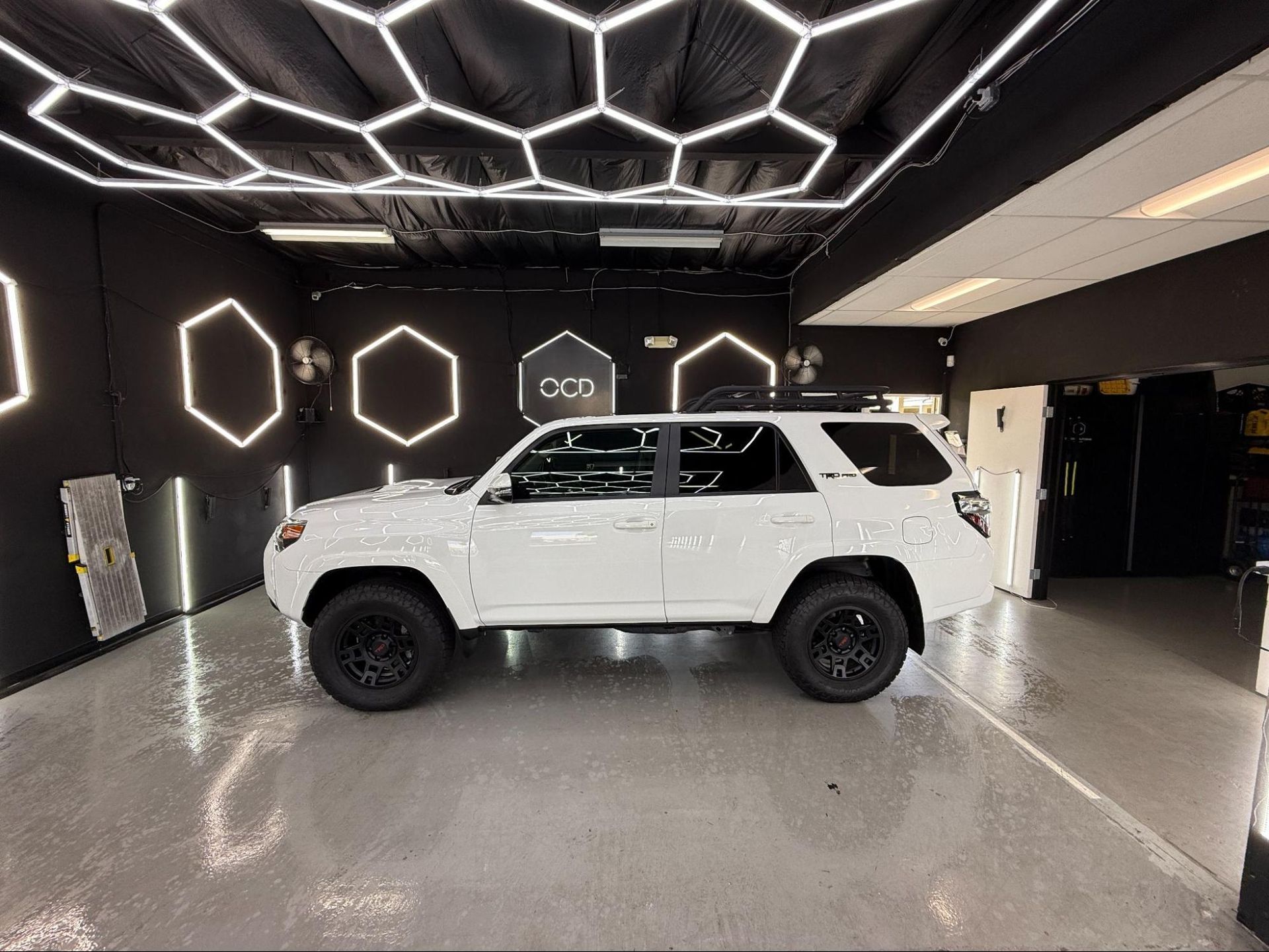 White SUV in a sleek showroom with geometric LED ceiling lights and glossy gray floor