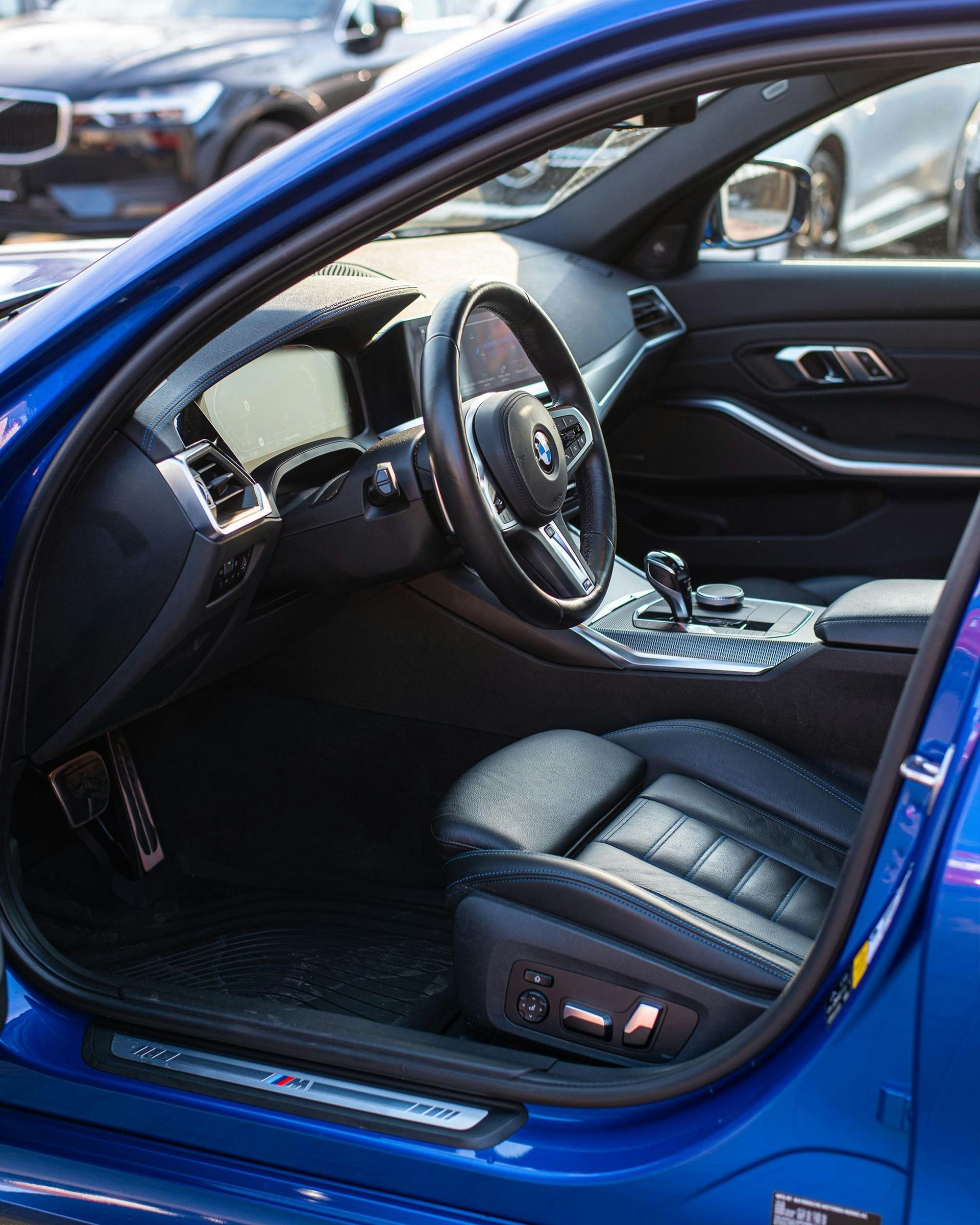 Blue sports car interior with black leather seats and open driver’s door