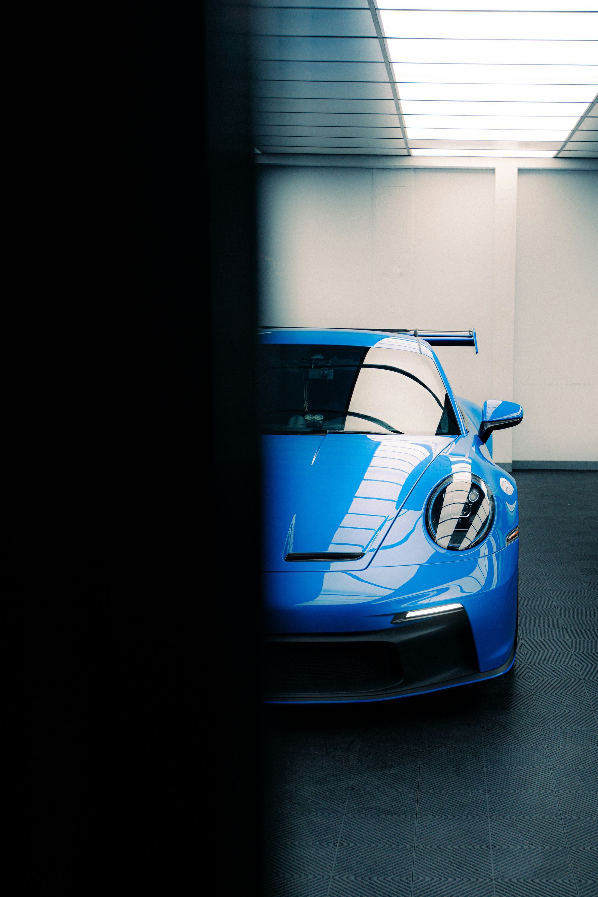 Blue sports car parked indoors under bright overhead lights.