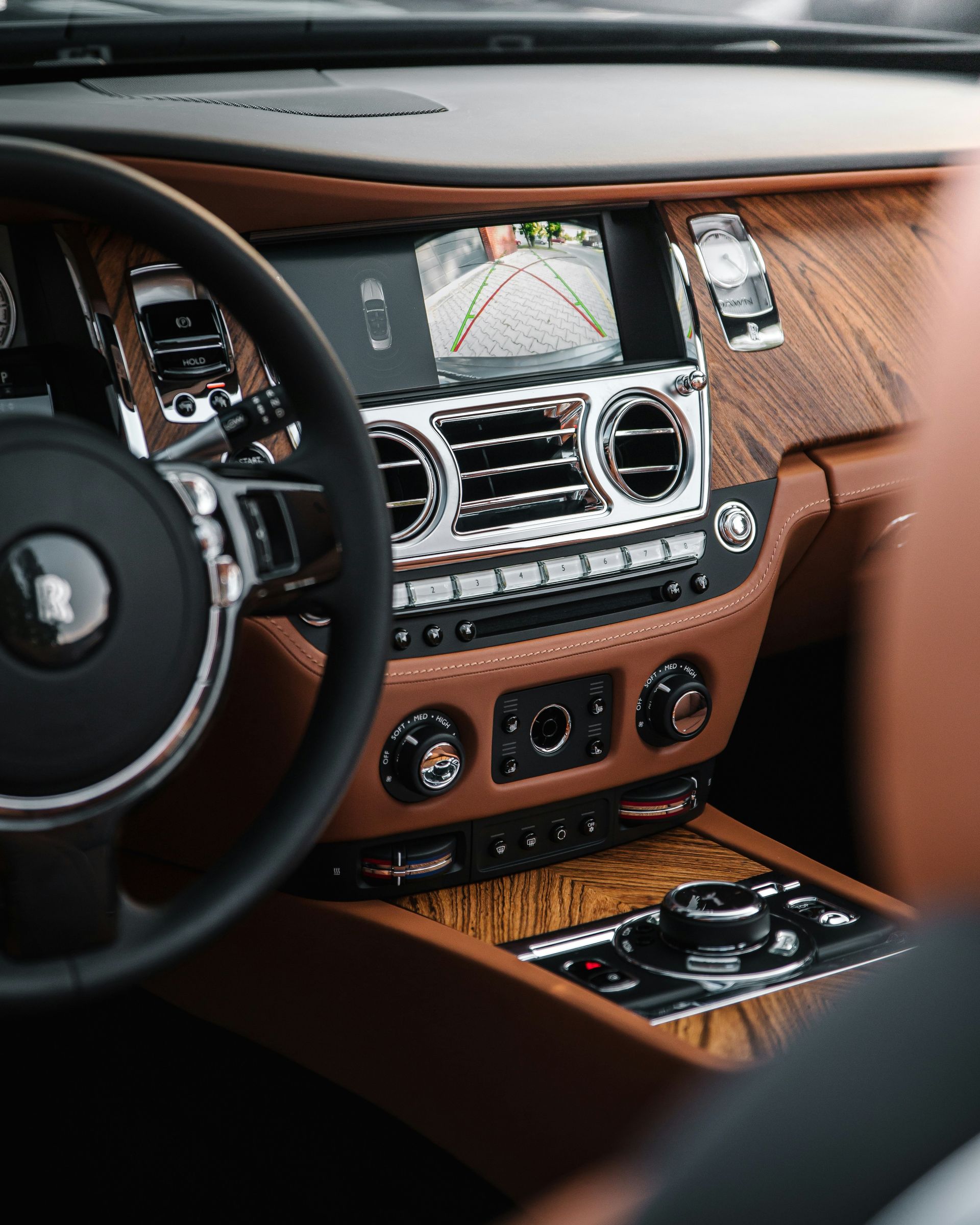 Luxury car dashboard with brown leather trim, touchscreen navigation, and climate controls