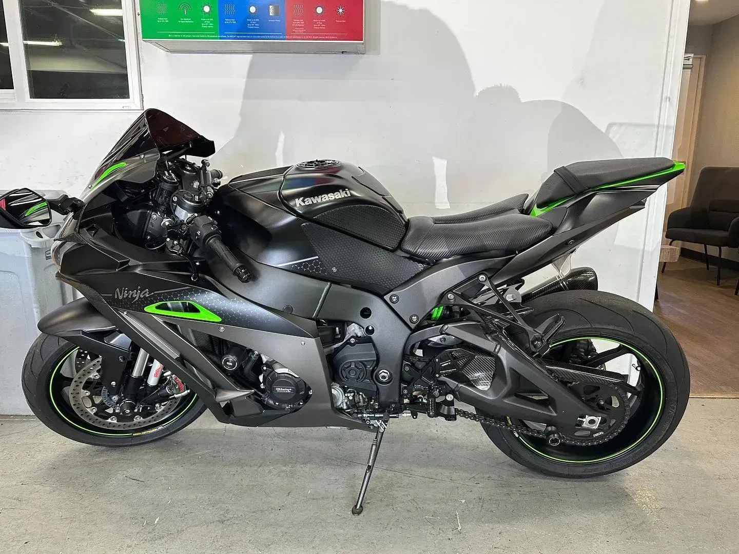 Black-and-green sport motorcycle parked indoors on a concrete floor.