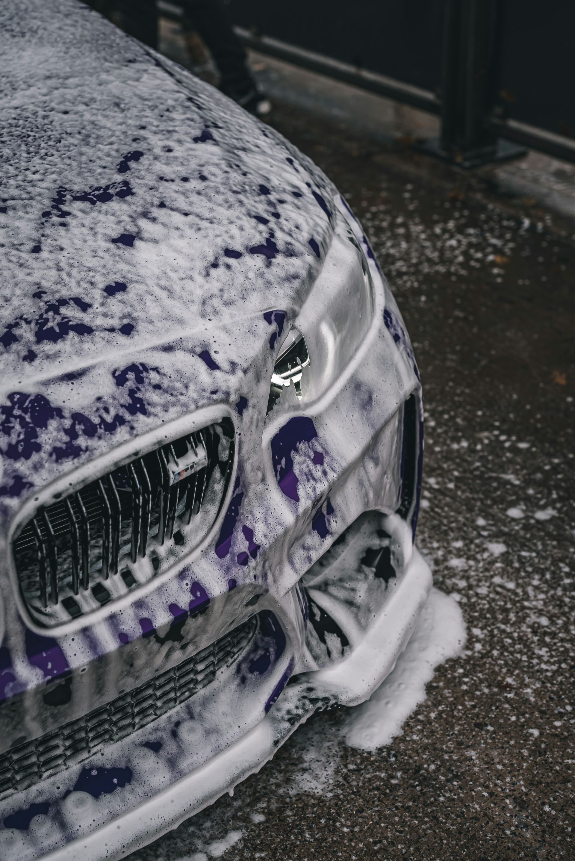 Snow-covered purple car front bumper on a wet road