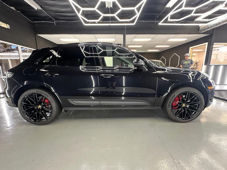 Black SUV with red brake calipers displayed indoors under geometric ceiling lights
