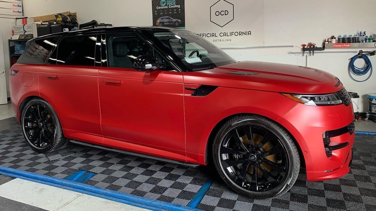 Red convertible sports car in a workshop, with black wheels and a glossy red body.