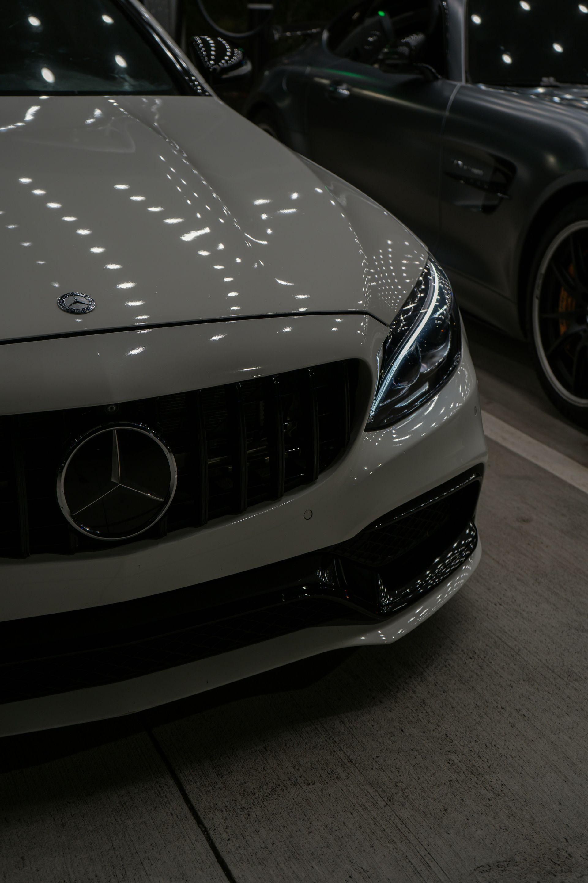 White Mercedes sports car displayed indoors under bright showroom lights, front-left view.