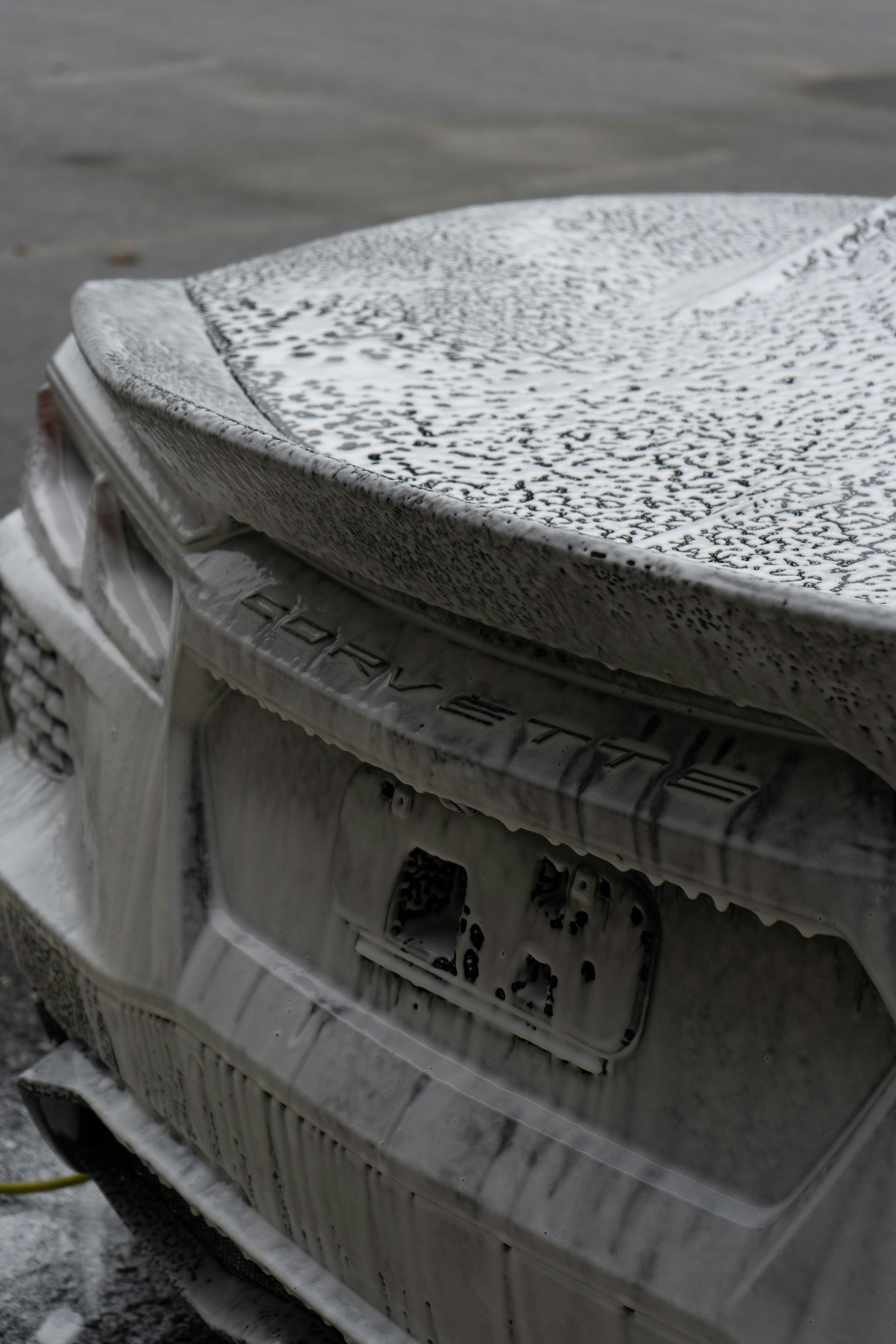 Snow-covered car trunk with icicles and a blurred rear license plate in winter.