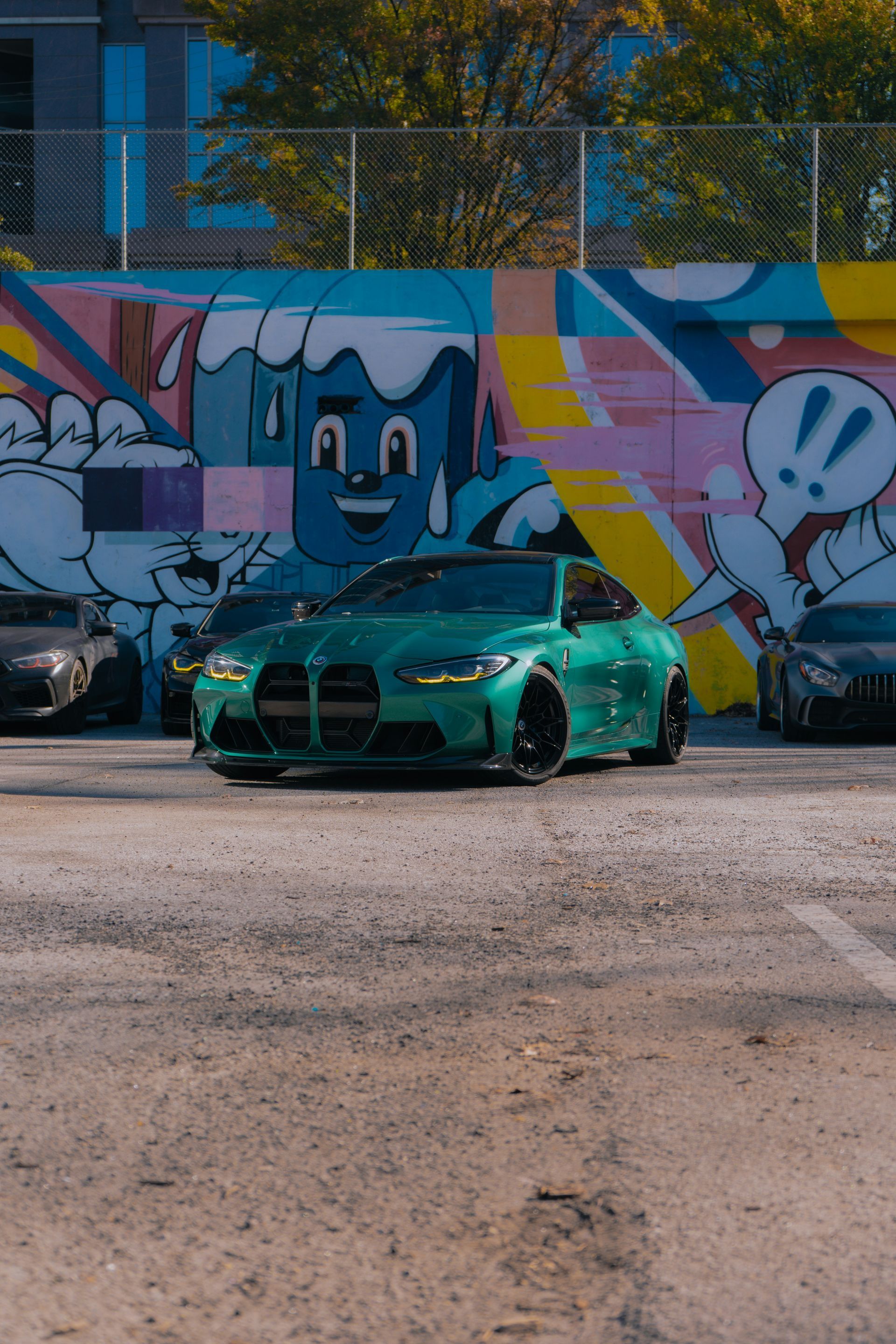 Green sports car parked before colorful graffiti mural in an urban lot