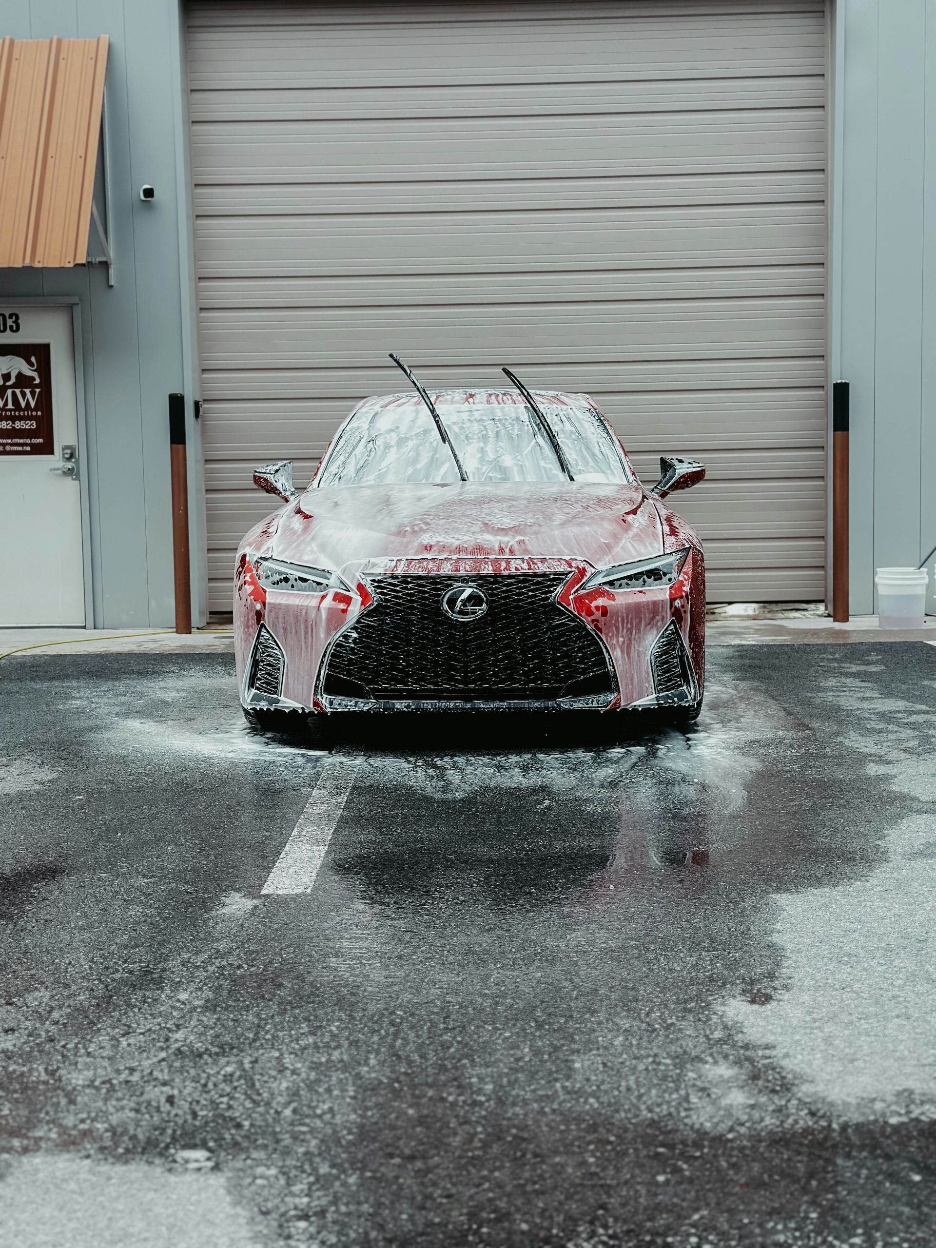 Red car covered in snow and ice parked in front of a closed garage door