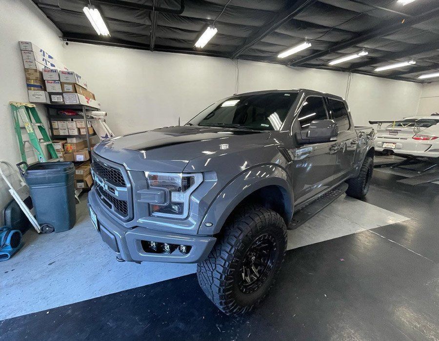 Gray lifted pickup truck in a garage with off-road tires and a custom front bumper
