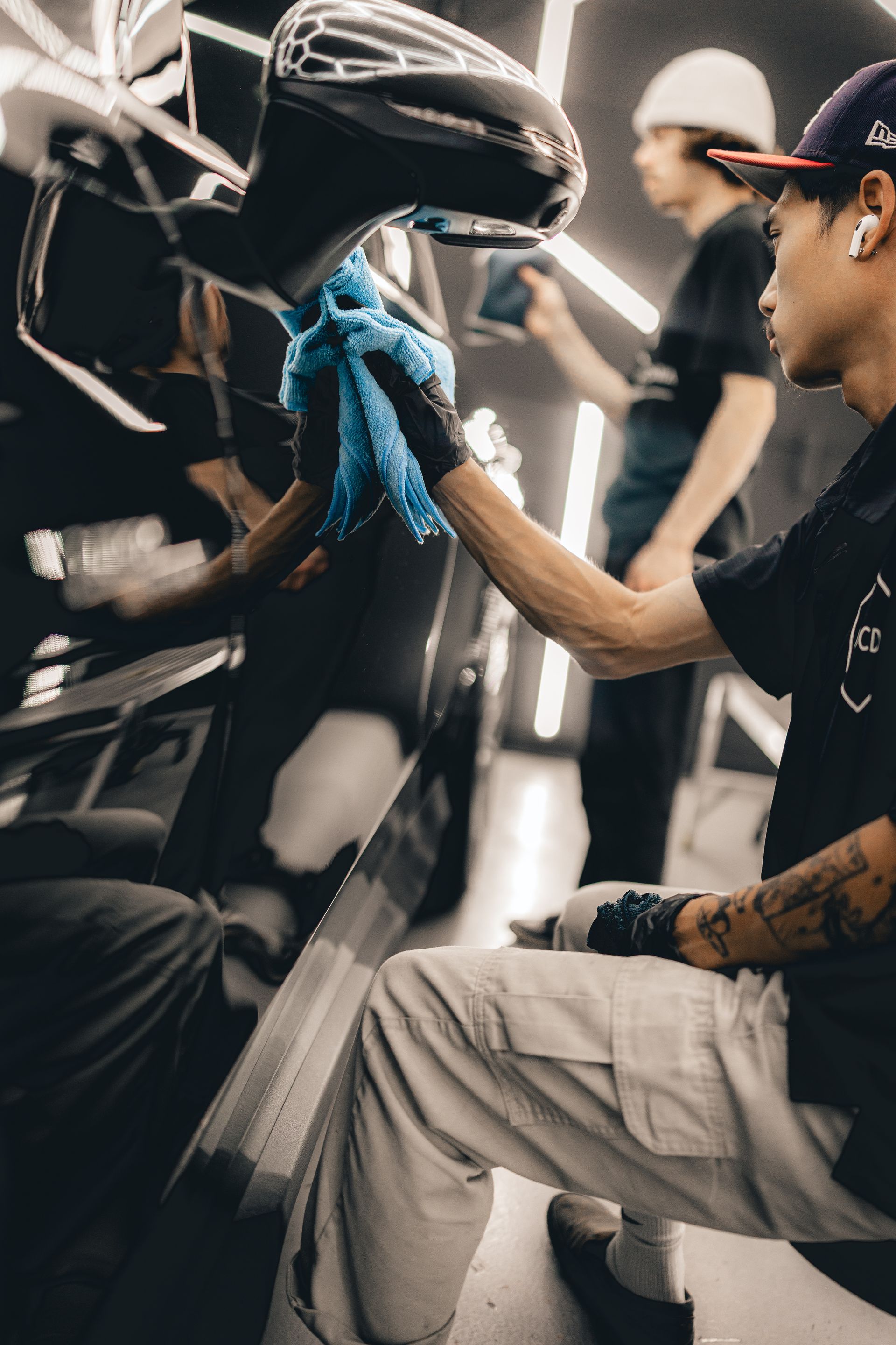Person cleaning a black helmet with a blue cloth in a garage or workshop