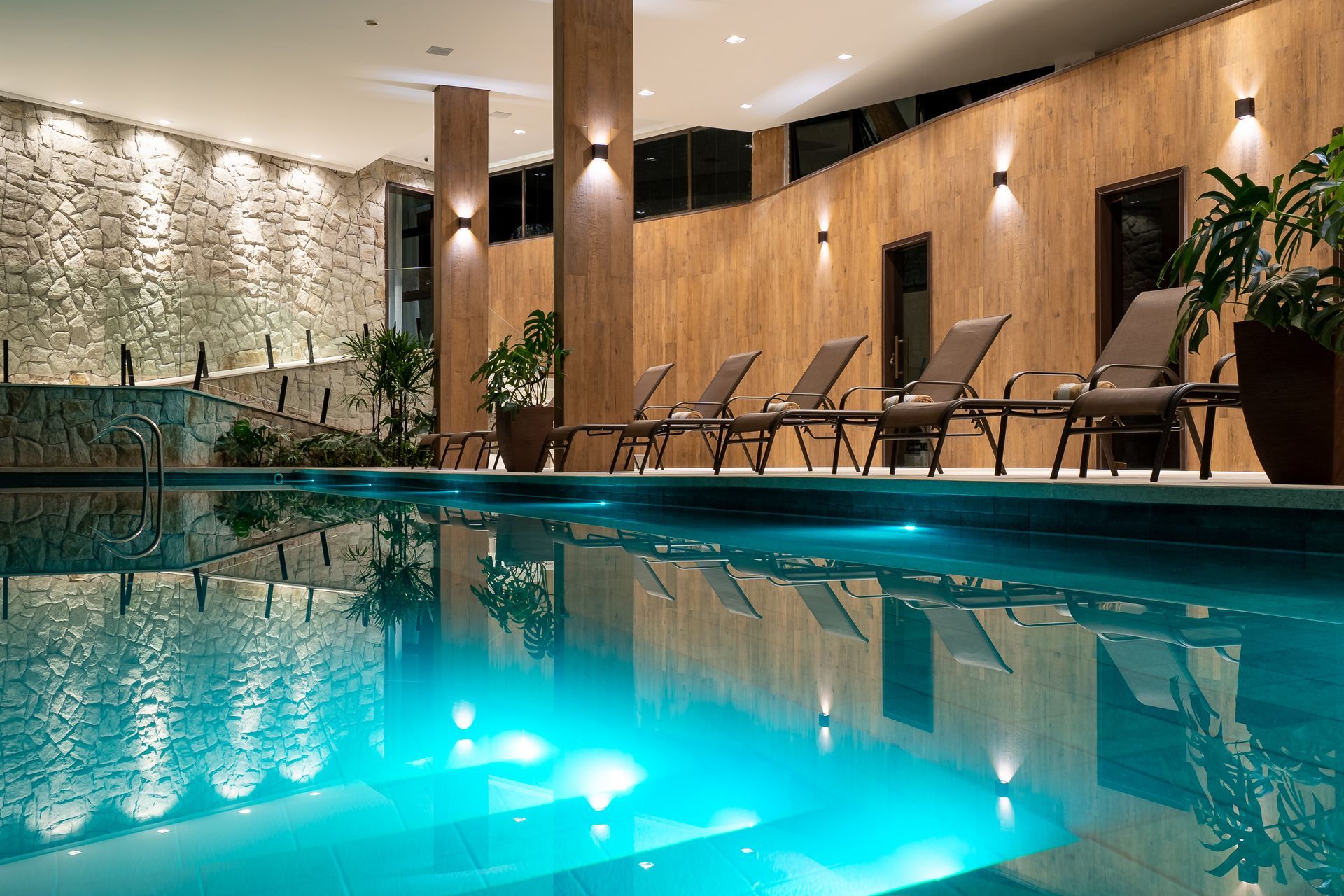 Uma grande piscina coberta com cadeiras ao redor à noite.
