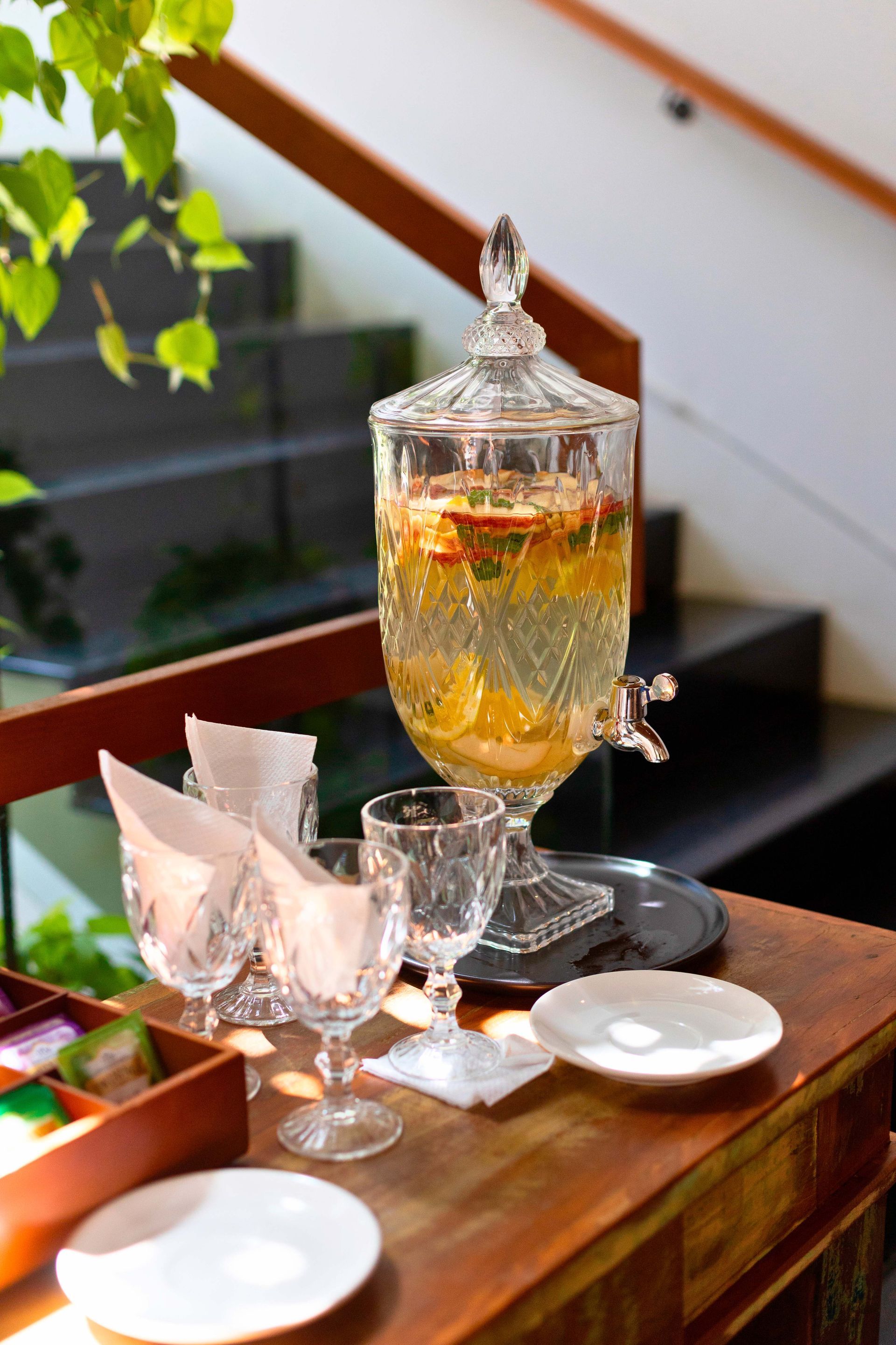 Uma mesa com pratos, copos e um dispensador de bebidas.