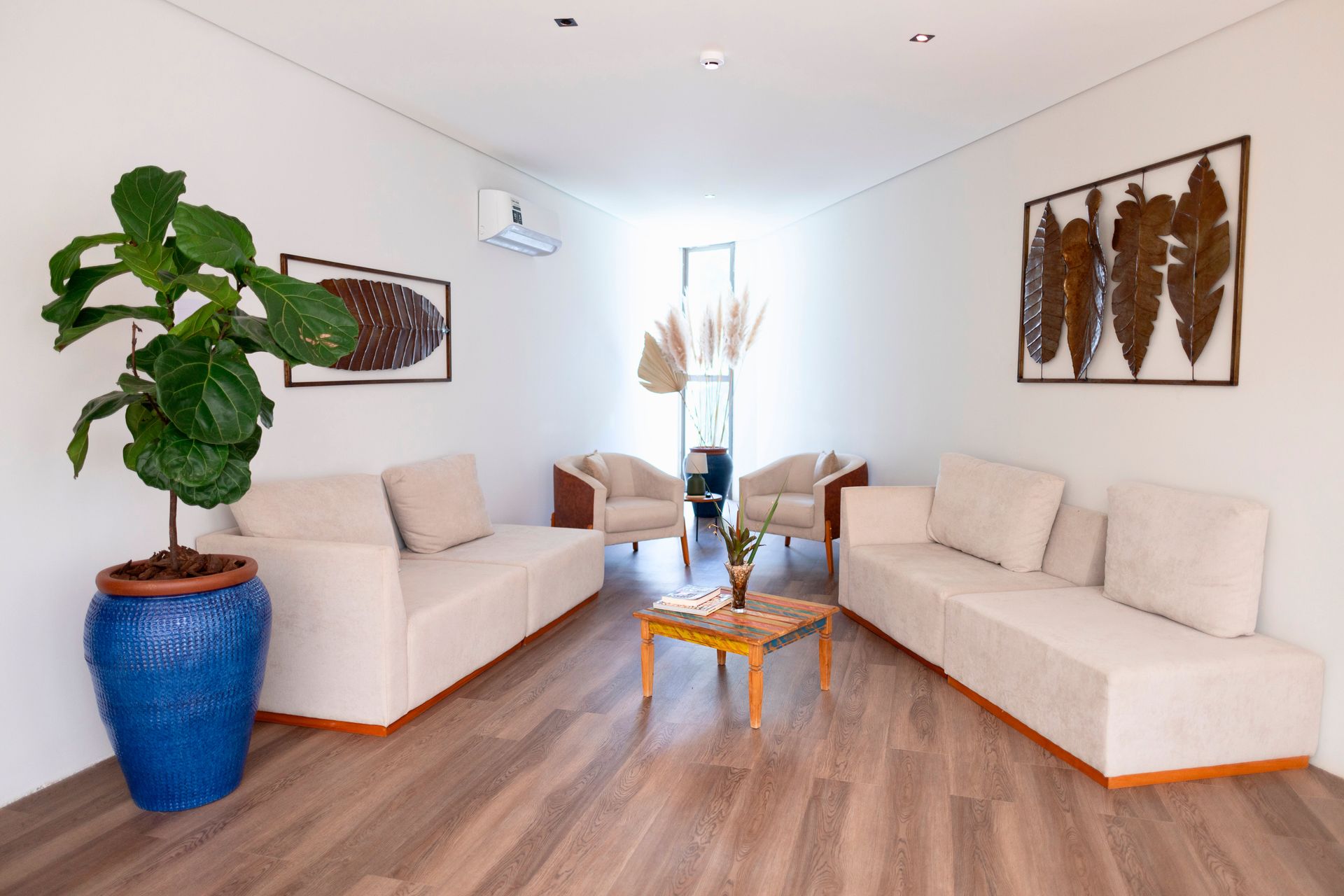 Uma sala de estar com sofás brancos, cadeiras, uma mesa e uma planta em vaso.