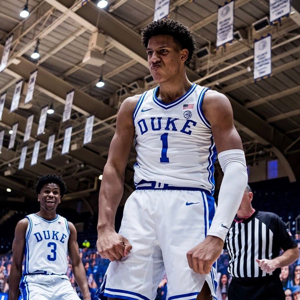 Basketball player in Duke Blue Devils uniform celebrating on court.