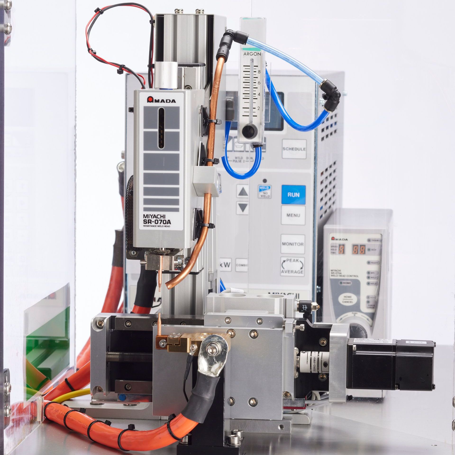 Industrial machine with red and blue tubing, metal components, and control panel on a workbench