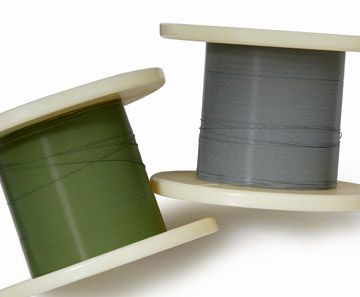 Two spools of thread, one olive green and one gray, leaning against each other on a white background