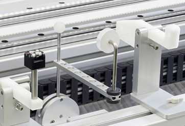 Industrial machine with white rollers, belts, and metal components on a production line
