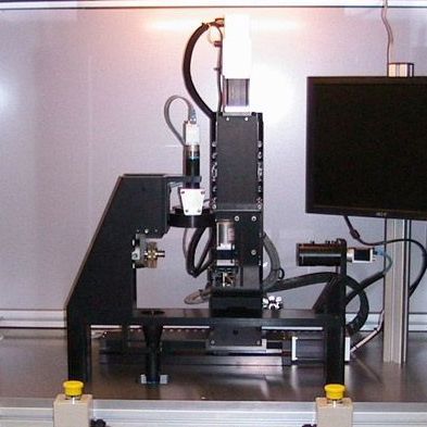 Black robotic machine on a table next to a monitor in a lab setting