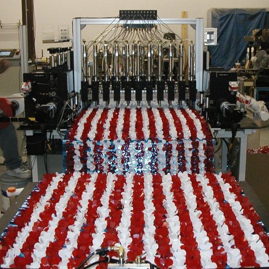 Large machine printing red, white, and blue striped fabric in a workshop